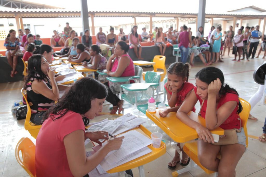 Mulher matriculando criança na escola municipal