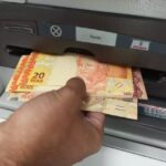 Homem sacando dinheiro em caixa eletrônico.