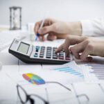 Homem anotando e calculando